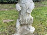 a statue of a bear standing on a rock in the grass