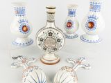 five vases and a bottle of liquor sitting on a table
