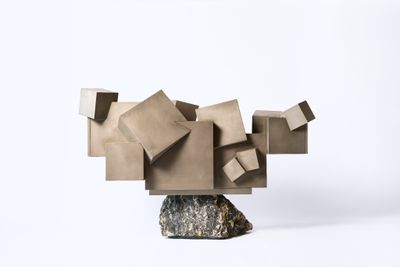 une sculpture réalisée à partir de blocs de carton posés sur un rocher