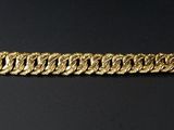 gros plan d'un bracelet en or sur une surface noire