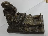 a bronze statue of a woman laying on a bed