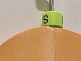 a close up of a wooden hanger with a green tag on it