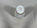 a white vase with a gold rim sitting on a white surface