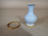 a small blue vase and a gold ring on a table