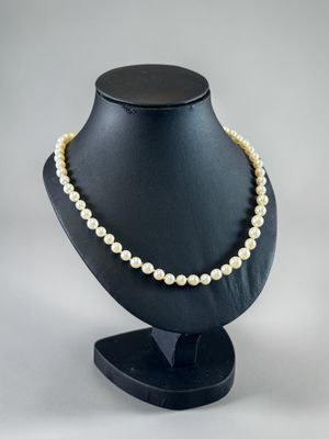 a white pearl necklace on a black mannequin stand