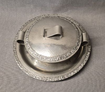 un plat en argent muni d'un couvercle, posé sur une table