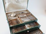 a green box with silverware in it on a white surface
