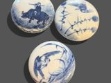 three blue and white balls with designs on them sitting on a table