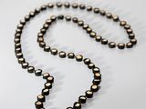 a close up of a necklace on a table with a white background