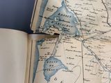 un livre ouvert, sur lequel figure une carte, posé sur une table