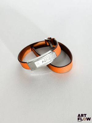 pair of orange leather bracelets with silver clasps on a white surface