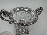 a silver bowl on a stand with a spoon next to it
