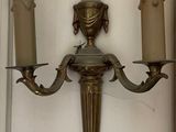 two candles on the wall next to a wall sconce