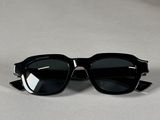 des lunettes de soleil noires ornées de pointes sur les branches, posées sur une table