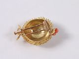 a gold brooch with a red bead on it