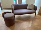 un canapé et un pouf dans un salon avec une fenêtre