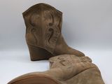 pair of tan cowboy boots on a white background with a white background