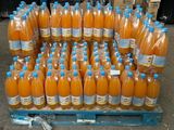 Des bouteilles de jus d'orange sont empilées sur une palette dans un entrepôt