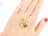 a woman ' s hand holding a gold ring with a cross on it