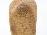 an old stoneware bottle with a wooden lid on a white surface