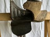 a horse saddle on a wooden stand with a hat on top of it