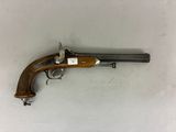 un vieux pistolet avec une poignée en bois sur une surface blanche