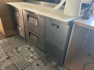 une photo d'une cuisine équipée d'appareils électroménagers en inox et d'un carrelage au sol