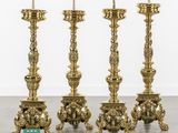 a set of four brass candlesticks with ornate designs