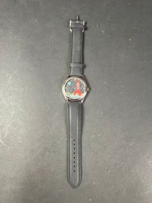 the watch is sitting on a black surface with a red flower on it