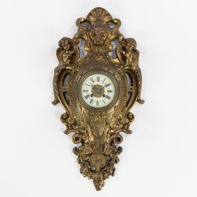 une horloge dorée accrochée au mur, sur fond blanc