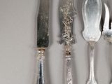 a lot of silver spoons and knives on the table