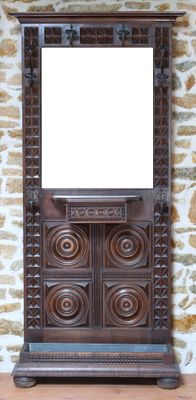 une armoire en bois surmontée d'un miroir, placée devant un mur en pierre