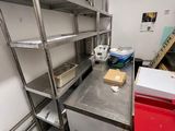 a kitchen with a lot of shelves and a red trash can