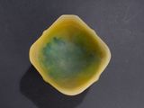 a yellow bowl with a green substance in it on a black surface