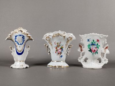 trois vases ornés de motifs floraux sont alignés sur une surface grise