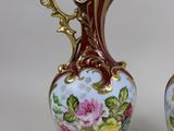 two vases with floral designs on them sitting on a white surface