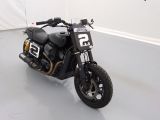 une moto noire garée dans une pièce aux murs blancs