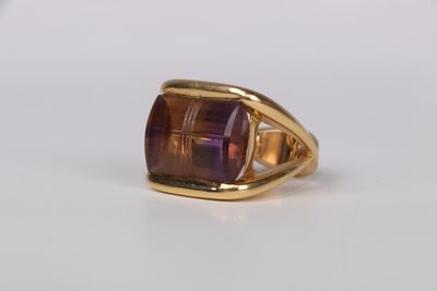 a close up of a gold ring with a purple stone