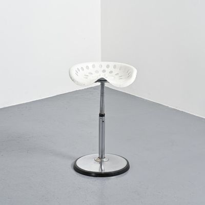 une photo d'un tabouret blanc dans un coin d'une pièce