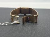 a gold bracelet with a metal clasp on a black surface