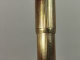 a close up of a gold colored pen on a white surface
