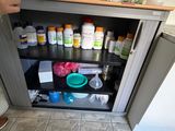 une personne debout devant une armoire remplie de flacons de médicaments