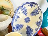a blue and white plate sitting on a table next to a vase