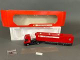 un petit camion rouge et un petit camion rouge dans une boîte