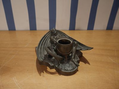un bougeoir orné d'un motif de chauve-souris, posé sur une table en bois
