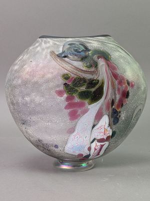a glass vase with a bird on it on a table
