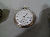 une montre de poche en argent posée sur une table à côté d'autres montres