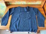 blue sweater sitting on a wooden bench in front of a wall