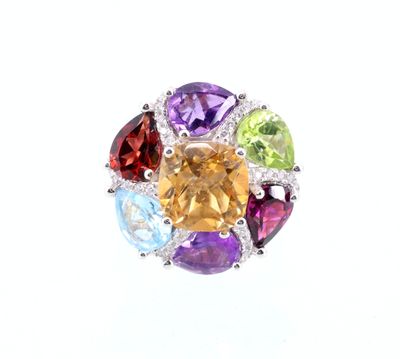 un gros plan d'une bague ornée de pierres multicolores sur fond blanc