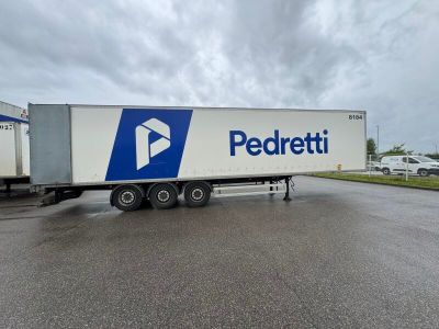a white semi truck with a blue and white logo parked in a parking lot